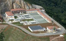 Aerial plan of a water treatment plant located in a hilly area surrounded by vegetation. Different types of water tanks can be seen